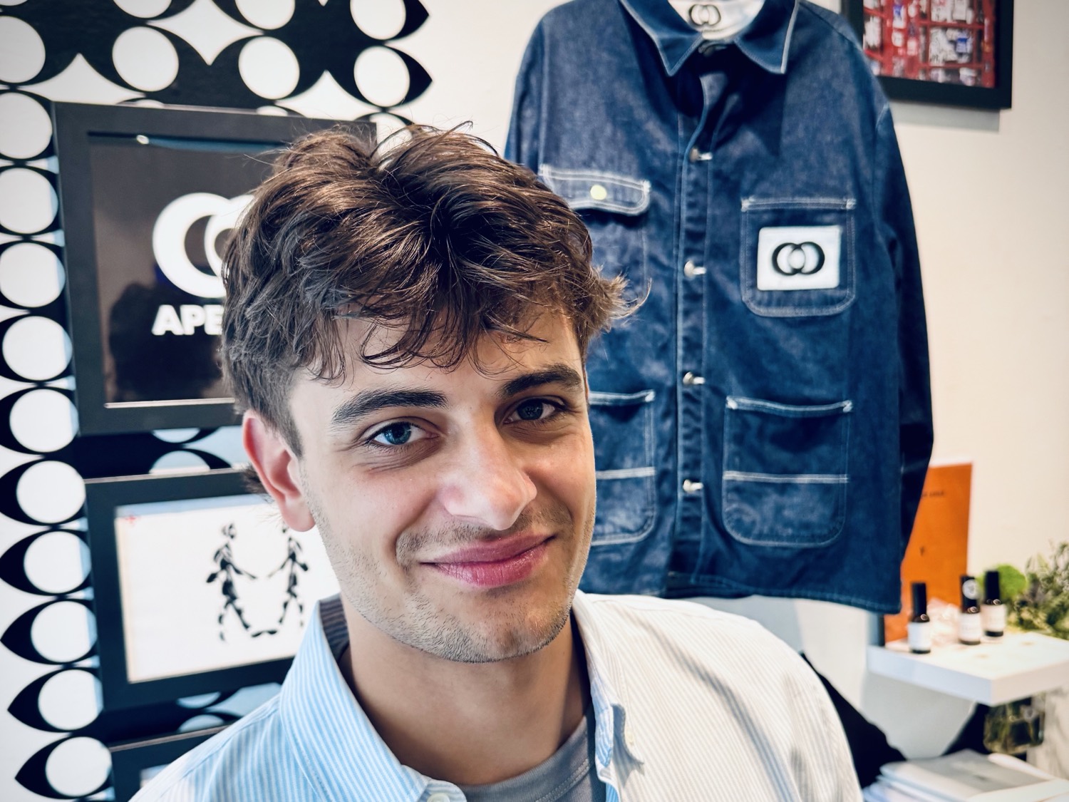 Kells McAuliffe in the studio, in front of an Apeiron poster and denim jacket.